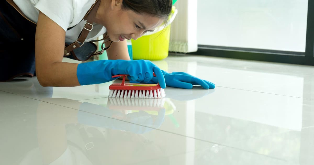 Une femme nettoie un carrelage après un chantier.