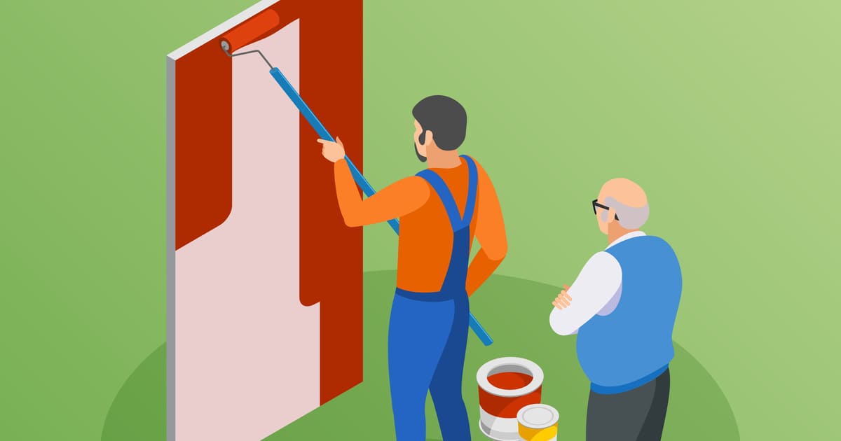 Un homme peint un mur en rouge sous la surveillance d'un autre homme les bras croisés.