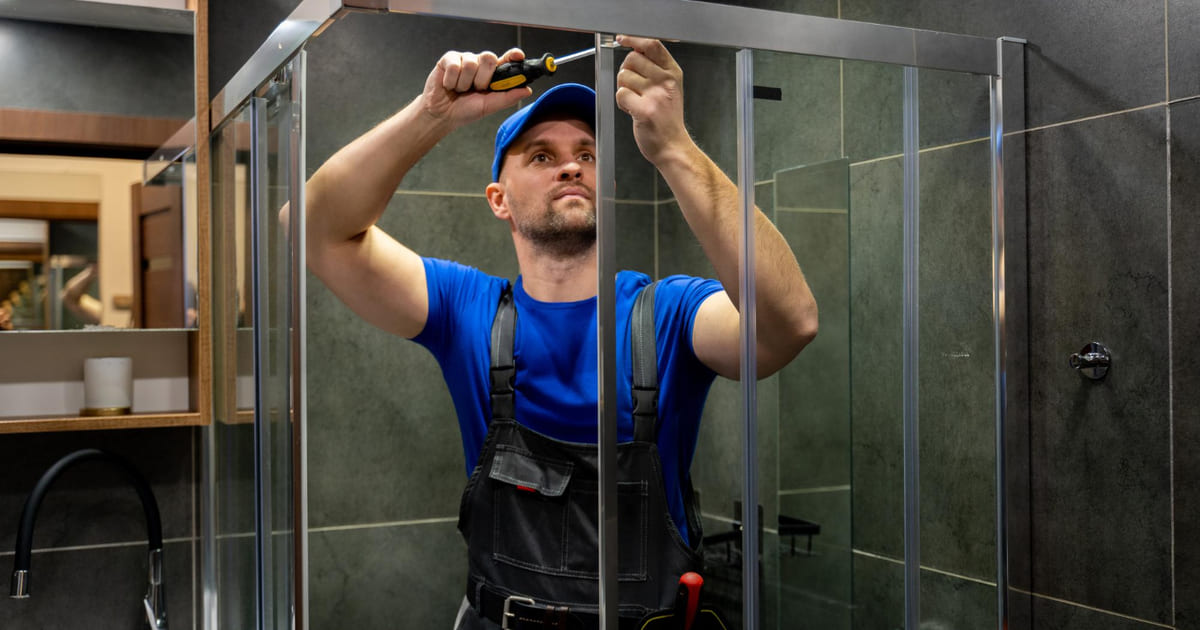 Un ouvrier installe une douche en travaux.