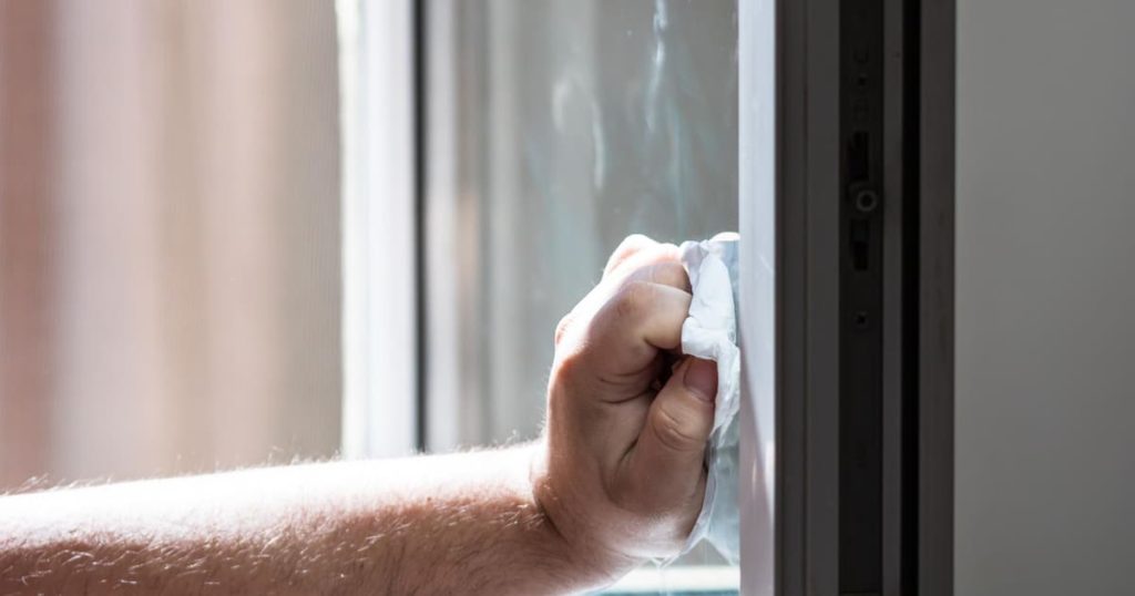 Une main avec un chiffon doux nettoie une vitre.