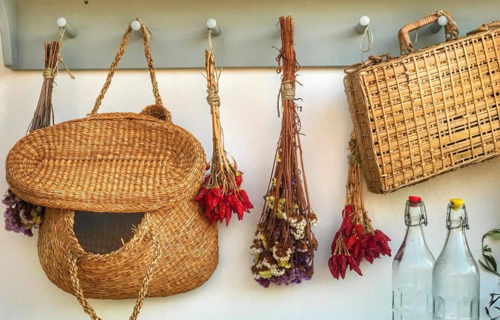 Paniers en osier et fleurs suspendus sur une patère dans une cuisine.